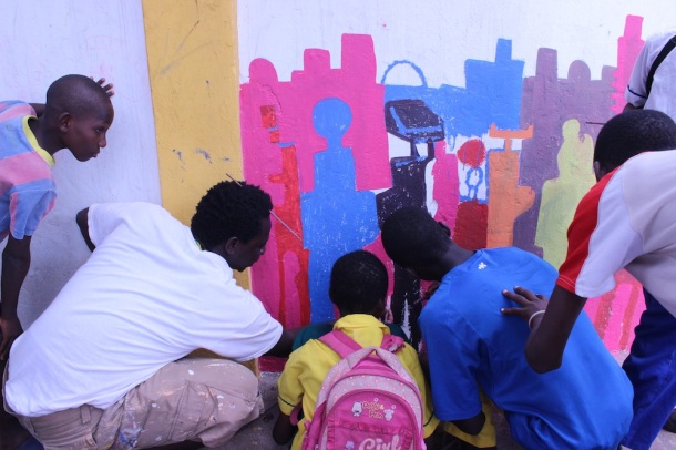 Musah Swallah, a local artist and leader in NMA, paints with Nima youth along the wall. 